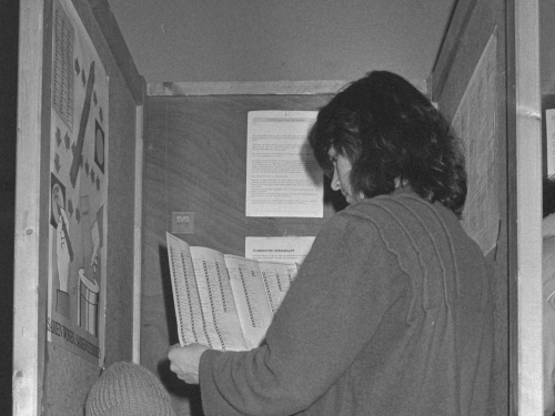 A man holds a ballot with many candidates.