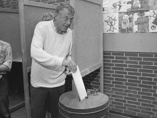 A man puts a voting ballot in a ballot box.